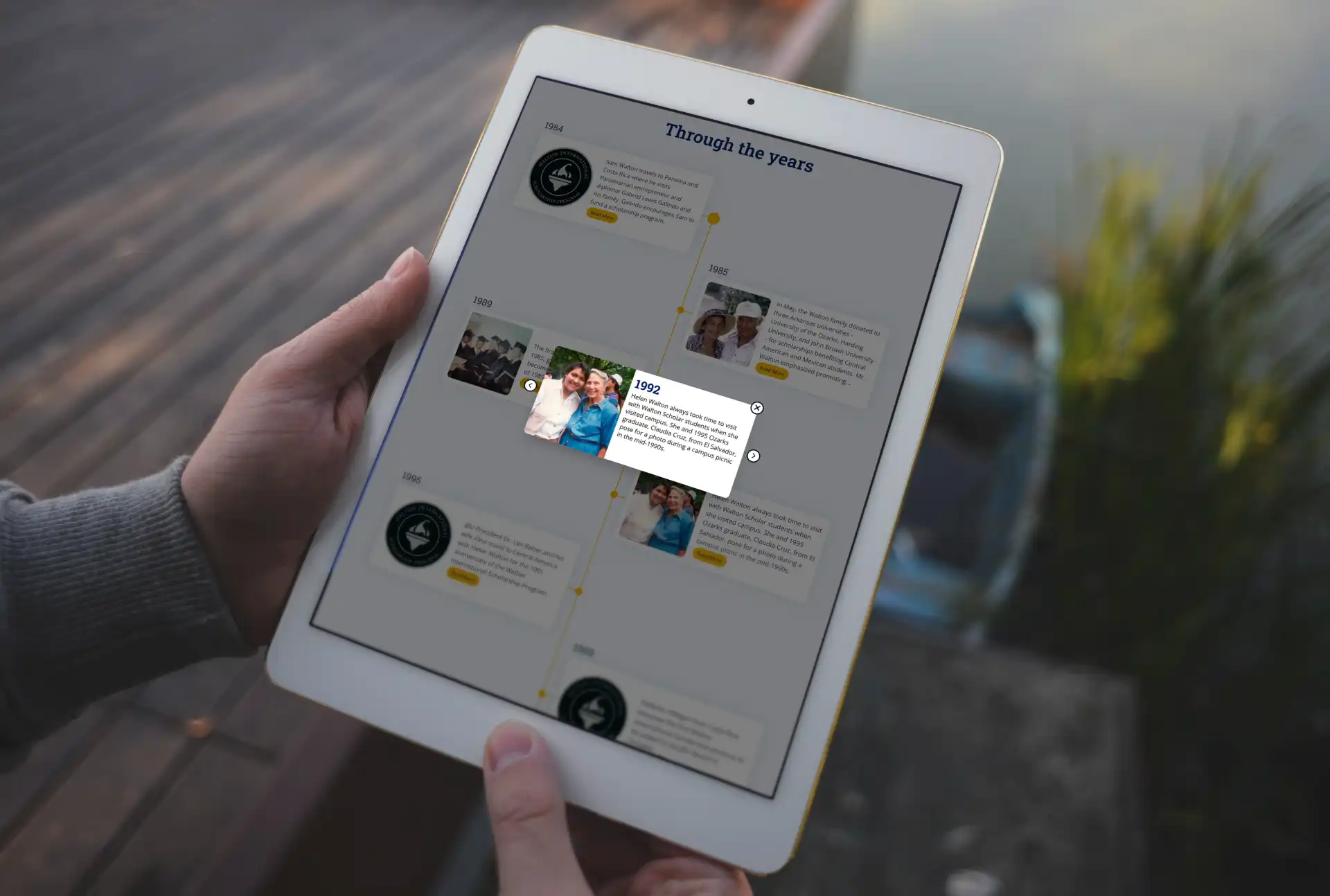 A person holding a tablet with a screenshot of website page called Through the years
